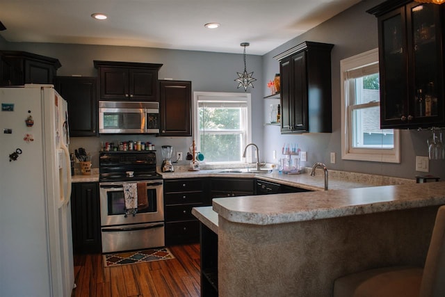 202 Wisconsin St, Mauston, WI 53948 - kitchen featuring stainless steel appliances, a sink, dark wood-type flooring, light countertops, and a peninsula