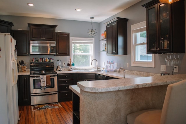 202 Wisconsin St, Mauston, WI 53948 - kitchen with appliances with stainless steel finishes, light countertops, dark wood-style floors, a sink, and a peninsula