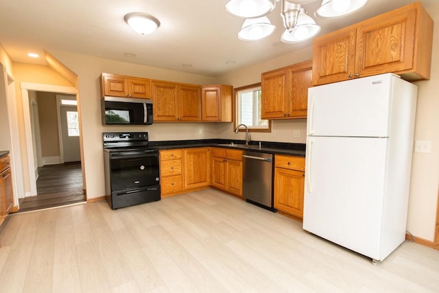 217 E Division St, Dodgeville, WI 53533 - kitchen with appliances with stainless steel finishes, a sink, dark countertops, light wood-type flooring, and brown cabinetry