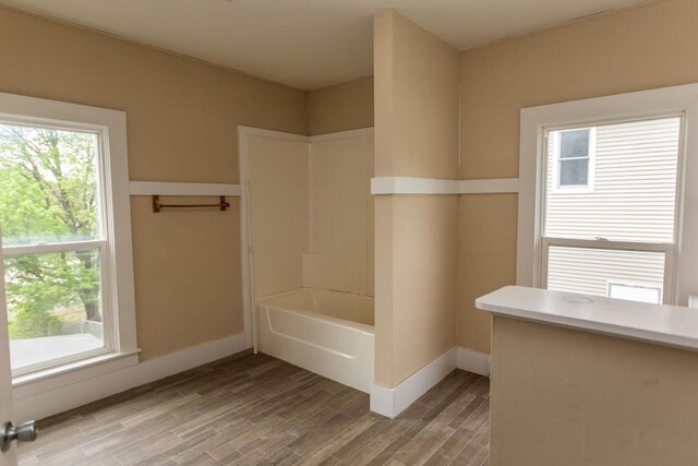 217 E Division St, Dodgeville, WI 53533 - bathroom with healthy amount of natural light, wood finished floors, baseboards, and tub / shower combination