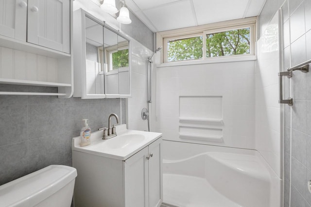 745 Carver Ln, Menasha, WI 54952 - bathroom featuring a shower, tile walls, vanity, toilet, and tasteful backsplash
