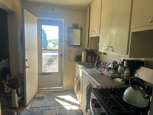 533 High Ave, Oshkosh, WI 54901 - kitchen featuring a sink, backsplash, stainless steel gas stove, white cabinets, and crown molding