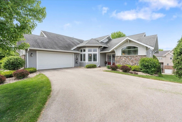 1814 Masters Ln, Madison, WI 53719 - view of front of home with asphalt driveway, a garage, stone siding, a shingled roof, and a front lawn