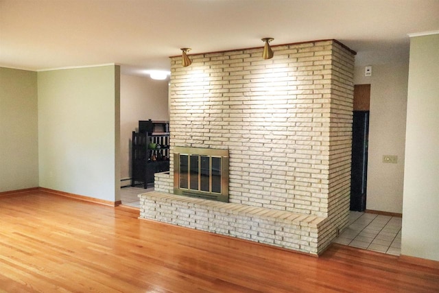 1007 Franklin St, Sauk City, WI 53583 - unfurnished living room with wood finished floors, a fireplace, baseboards, crown molding, and a baseboard radiator