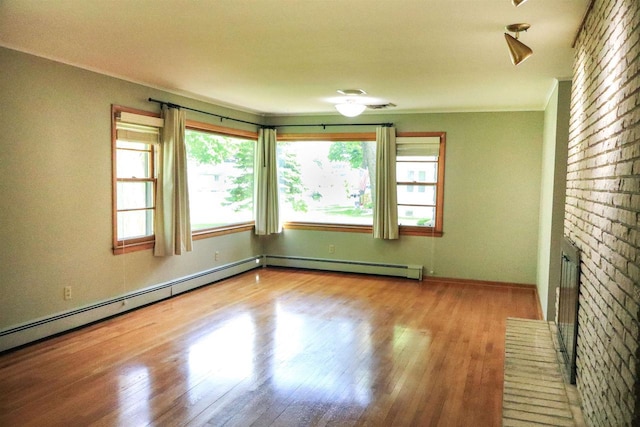 1007 Franklin St, Sauk City, WI 53583 - spare room with wood finished floors, plenty of natural light, a baseboard radiator, ornamental molding, and baseboards
