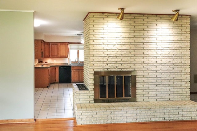 1007 Franklin St, Sauk City, WI 53583 - kitchen with dishwasher, a sink, brown cabinetry, light tile patterned flooring, and light countertops