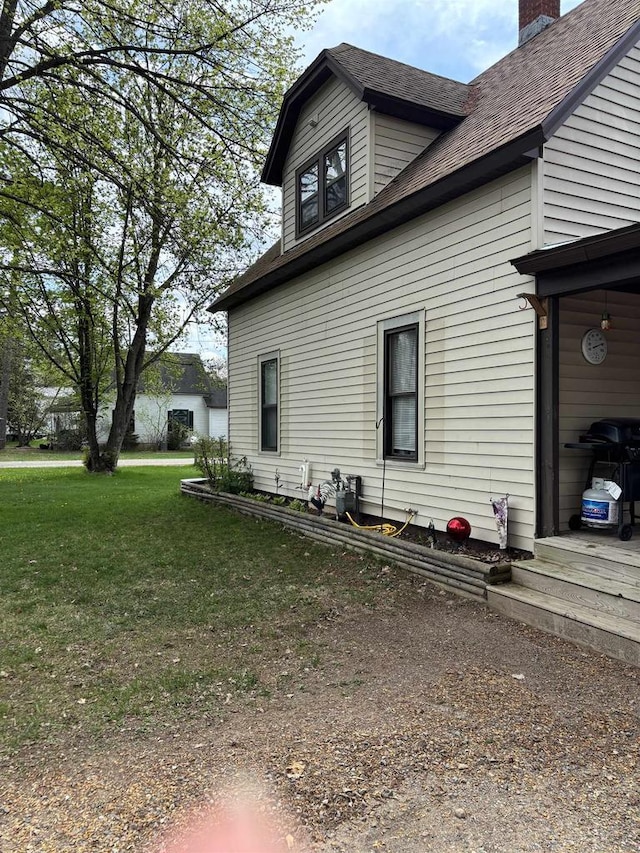307 E Washington St, Crandon, WI 54520 - view of property exterior featuring a chimney, a shingled roof, and a yard