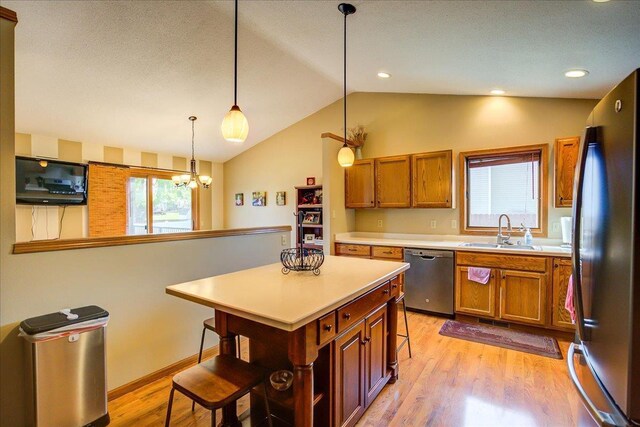 182 Ames St, Oregon, WI 53575 - kitchen with stainless steel appliances, a sink, lofted ceiling, a kitchen bar, and brown cabinetry