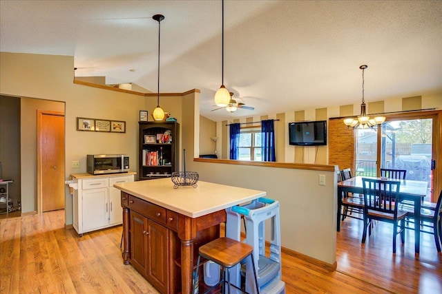 182 Ames St, Oregon, WI 53575 - kitchen with stainless steel microwave, vaulted ceiling, a chandelier, light wood-type flooring, and white cabinetry