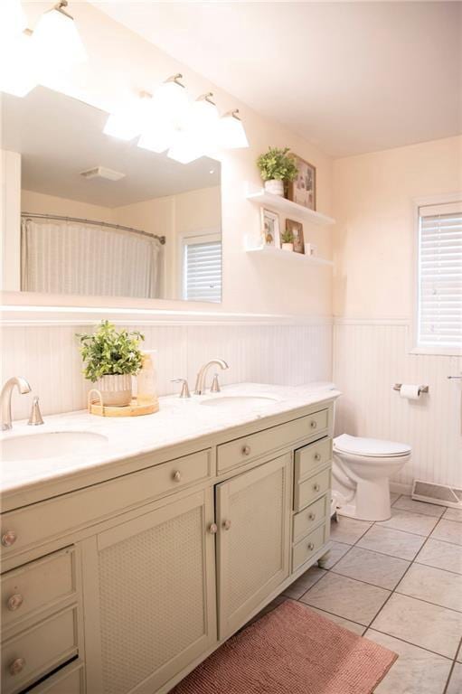 2702 Clark Pl, Eau Claire, WI 54701 - full bathroom featuring double vanity, toilet, a wainscoted wall, and tile patterned flooring