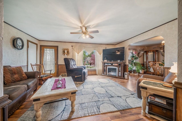 W8749 Hunters Rd, Hortonville, WI 54944 - living room featuring ceiling fan, arched walkways, a fireplace, a wainscoted wall, and wood finished floors