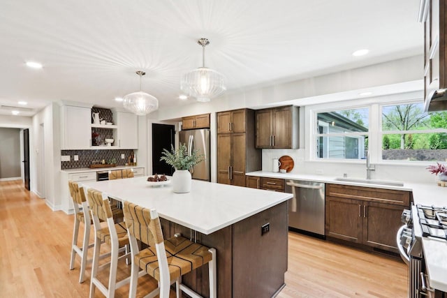 6020 Briarclift Ct, Greendale, WI 53129 - kitchen with appliances with stainless steel finishes, a sink, open shelves, a center island, and a kitchen bar