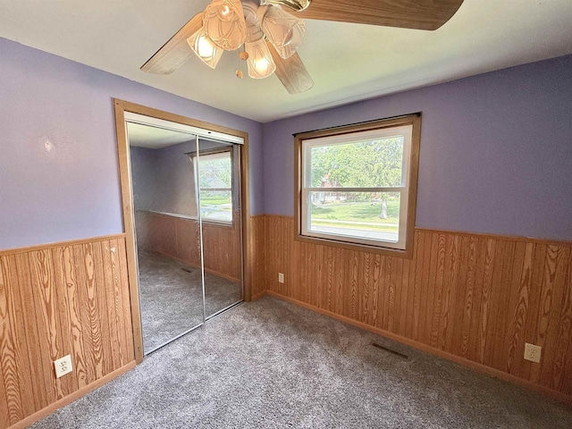 519 Rogers St, Milton, WI 53563 - unfurnished bedroom with wainscoting, wood walls, carpet flooring, ceiling fan, and a closet