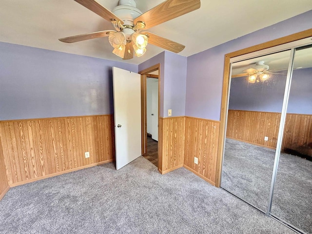 519 Rogers St, Milton, WI 53563 - unfurnished bedroom featuring wooden walls, carpet, wainscoting, a ceiling fan, and a closet