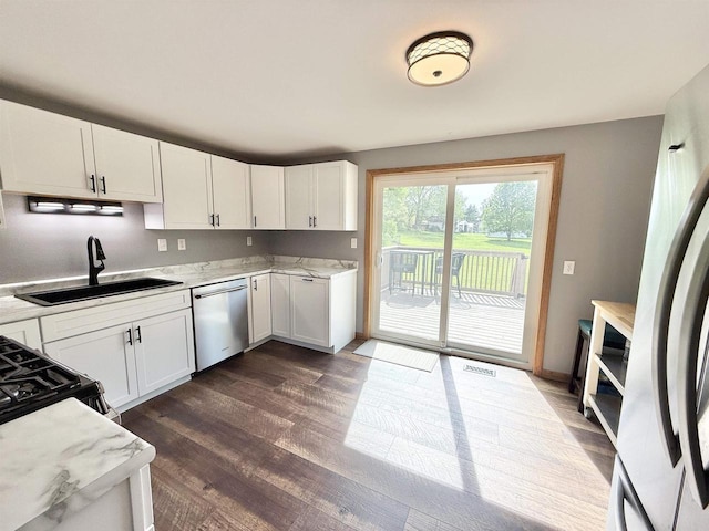 519 Rogers St, Milton, WI 53563 - kitchen with stainless steel appliances, a sink, white cabinetry, dark wood-type flooring, and light stone counters