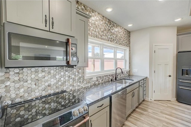 17690 Clayton Ave, Rosemount, MN 55068 - kitchen featuring appliances with stainless steel finishes, a sink, dark stone counters, gray cabinetry, and light wood-type flooring