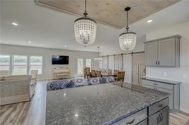 17690 Clayton Ave, Rosemount, MN 55068 - kitchen with a chandelier, gray cabinetry, light wood-style flooring, dark stone countertops, and a barn door