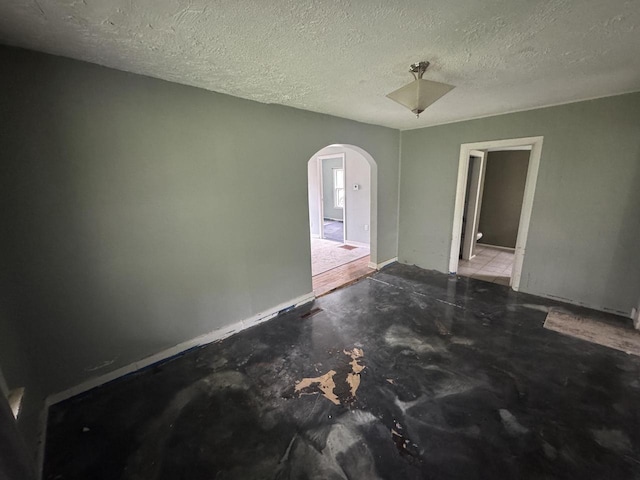 30728 113th St, Wilmot, WI 53181 - empty room with arched walkways, a textured ceiling, and unfinished concrete flooring