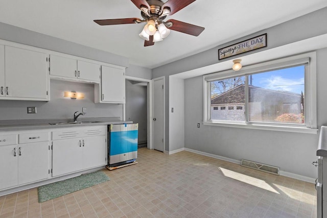 4415 S 5th St, Milwaukee, WI 53207 - kitchen with a sink, dishwasher, light countertops, white cabinets, and baseboards