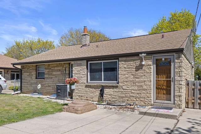 4415 S 5th St, Milwaukee, WI 53207 - back of property featuring stone siding, roof with shingles, a chimney, and central AC unit