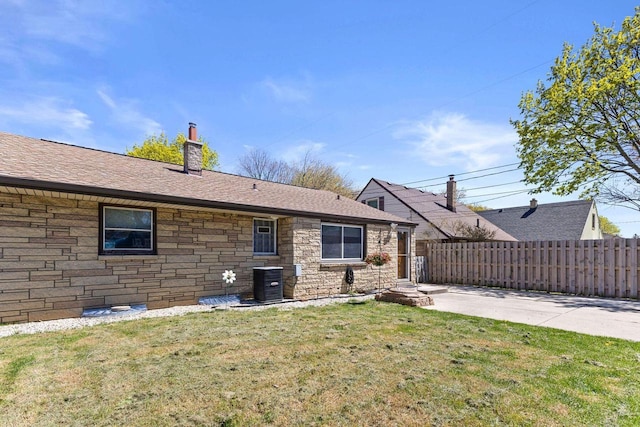 4415 S 5th St, Milwaukee, WI 53207 - rear view of property featuring a chimney, central AC unit, stone siding, and roof with shingles