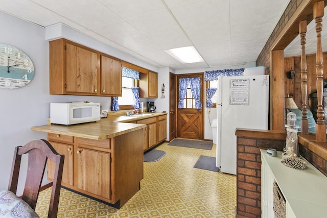 N7428 County Road J, Plymouth, WI 53073 - kitchen featuring white appliances, a peninsula, light countertops, a sink, and light floors