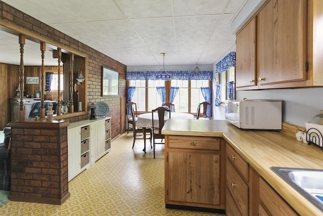 N7428 County Road J, Plymouth, WI 53073 - kitchen with white microwave, healthy amount of natural light, a peninsula, brown cabinets, and brick wall