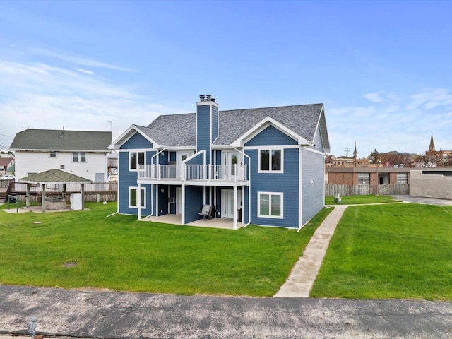 rear view of house featuring a chimney, a patio area, a wooden deck, and a shingled roof