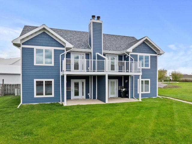 back of property with a patio, a lawn, a chimney, and a shingled roof