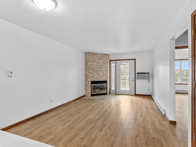 unfurnished living room with a baseboard radiator, light wood finished floors, an AC wall unit, and a fireplace