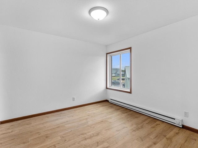 empty room with baseboard heating, light wood-style flooring, and baseboards