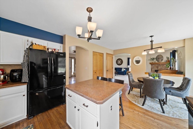1755 Laura Ln, Port Washington, WI 53074 - kitchen with freestanding refrigerator, arched walkways, light wood finished floors, and white cabinets