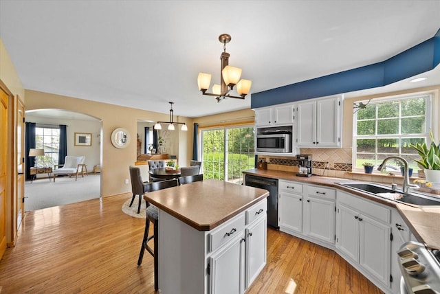 1755 Laura Ln, Port Washington, WI 53074 - kitchen with a sink, stainless steel microwave, black dishwasher, arched walkways, and white cabinetry