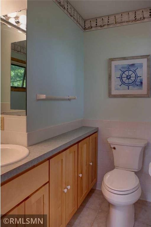 802 Flos Ct, Amery, WI 54001 - bathroom with tile patterned floors, vanity, toilet, tile walls, and a wainscoted wall