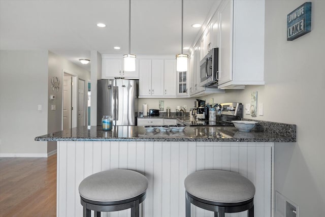 131 Lance Dr Unit 14, Twin Lakes, WI 53181 - kitchen with stainless steel appliances, dark stone counters, wood finished floors, a peninsula, and recessed lighting