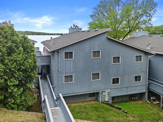 131 Lance Dr Unit 14, Twin Lakes, WI 53181 - back of property with a shingled roof, a chimney, a water view, and a yard