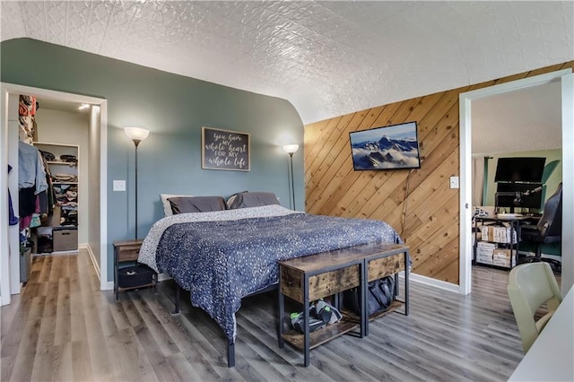 W4505 890th Ave, Baldwin, WI 54002 - bedroom with baseboards, a walk in closet, wood finished floors, and wood walls