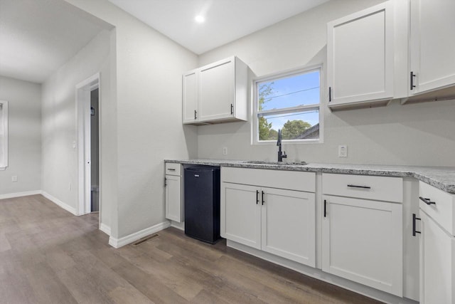 2976 N 40th St, Milwaukee, WI 53210 - kitchen with a sink, white cabinetry, dark wood finished floors, baseboards, and light stone countertops