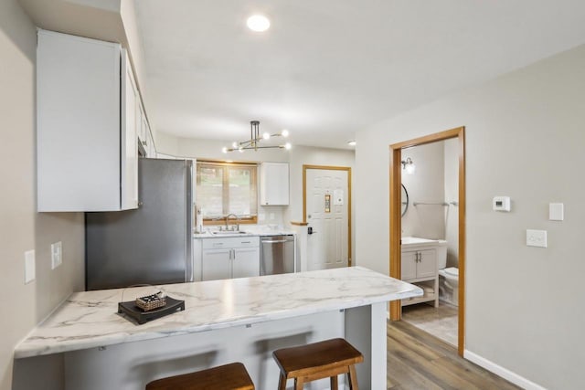 874 Xanadu Rd, Wisconsin Dells, WI 53965 - kitchen featuring stainless steel appliances, a peninsula, light wood-style floors, a kitchen bar, and a sink