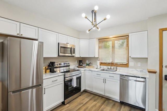 874 Xanadu Rd, Wisconsin Dells, WI 53965 - kitchen with stainless steel appliances, a sink, white cabinetry, and a chandelier