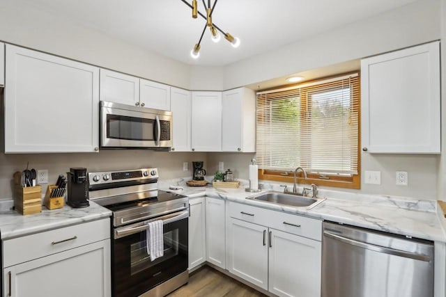 874 Xanadu Rd, Wisconsin Dells, WI 53965 - kitchen featuring stainless steel appliances, a sink, white cabinets, light stone counters, and light wood-style floors