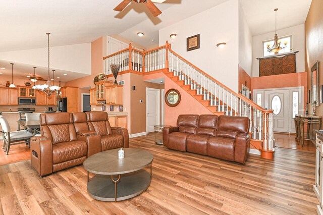 8940 Marie Ct, Mount Pleasant, WI 53406 - living area featuring a ceiling fan, a chandelier, high vaulted ceiling, stairs, and light wood-style flooring