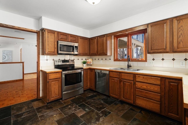 6208 Indian Mound Dr, Mcfarland, WI 53558 - kitchen featuring stainless steel appliances, a sink, decorative backsplash, light countertops, and brown cabinets