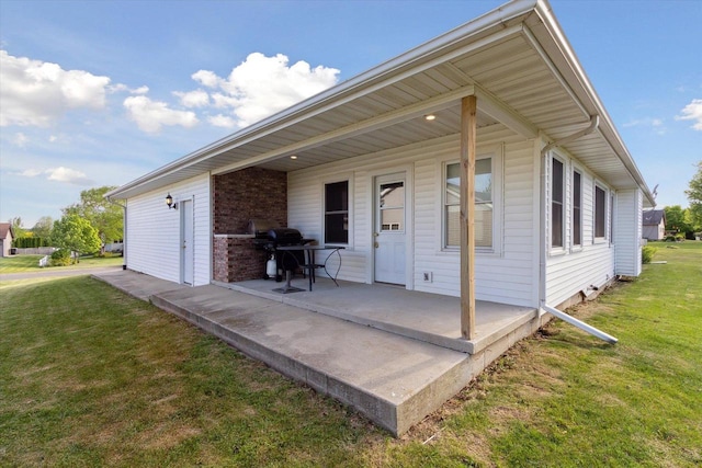 605 E Rime St, Orfordville, WI 53576 - back of house with a lawn, brick siding, and a patio