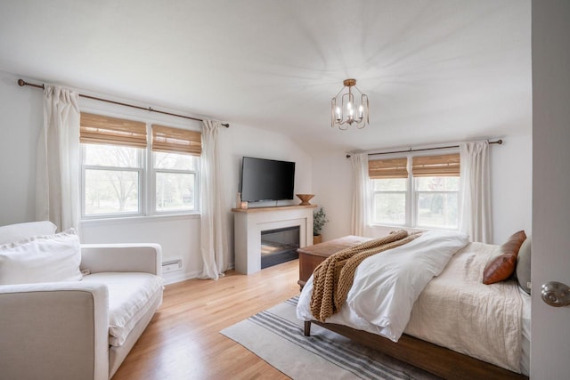 6935 N Yates Rd, Fox Point, WI 53217 - bedroom with a chandelier, a glass covered fireplace, wood finished floors, and a baseboard radiator