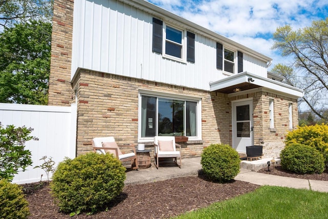 6935 N Yates Rd, Fox Point, WI 53217 - rear view of property with board and batten siding, brick siding, and a patio