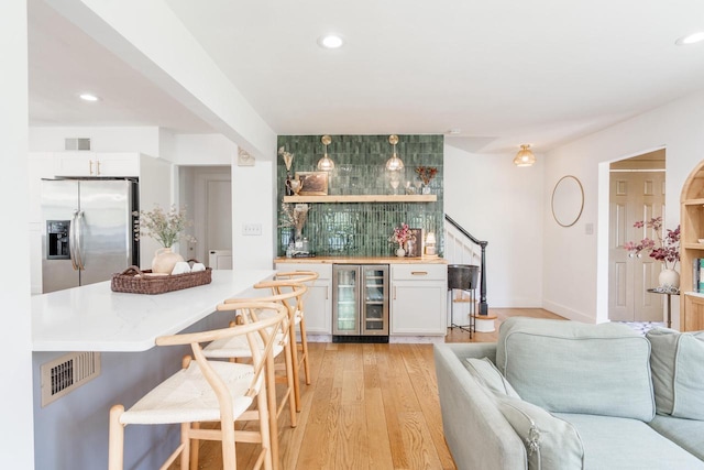 6935 N Yates Rd, Fox Point, WI 53217 - indoor wet bar featuring wine cooler, stainless steel refrigerator with ice dispenser, light wood-type flooring, recessed lighting, and stairs