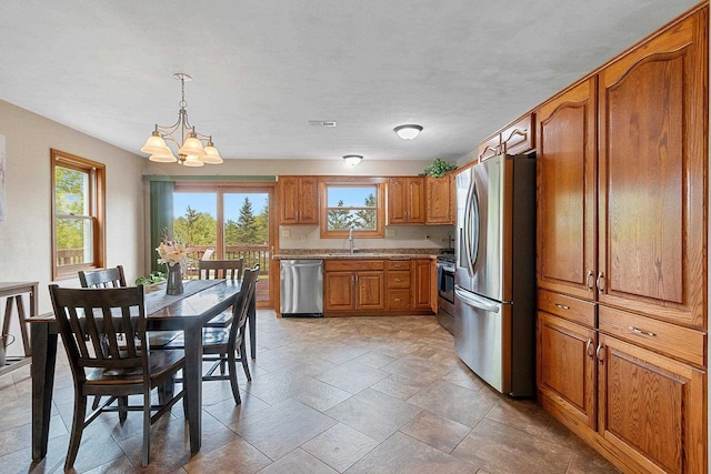 N3270 State Rd 76, Hortonville, WI 54944 - kitchen featuring appliances with stainless steel finishes, brown cabinetry, a sink, a chandelier, and decorative light fixtures