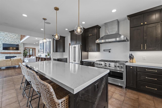 4230 Dalby Rd, Black Earth, WI 53515 - kitchen featuring wall chimney exhaust hood, high end appliances, backsplash, open floor plan, and a stone fireplace
