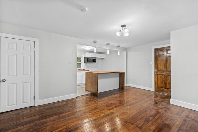 5015 N 25th St, Milwaukee, WI 53209 - kitchen with stainless steel microwave, dark wood finished floors, white cabinets, and baseboards